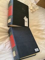 Two closed green hardcover Minkus stamp albums with red spine labels stacked on a bed