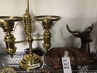 Photo showing the metal lamp with two lamp holders missing glass shades and the wooden deer statue with brass-colored horns and carved fur texture.