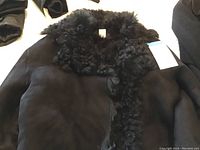 Close-up of collar and front showing black suede exterior and curly shearling lining