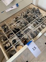 Drawer containing clear acrylic organizer with 30 compartments filled with black, white and silver earrings
