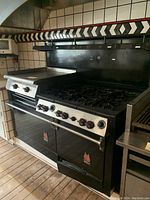 Front and left-side view of full range showing six-burner cooktop, griddle and dual oven doors