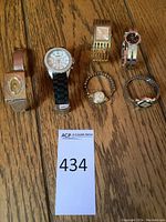 All six watches arranged on wood surface with lot card