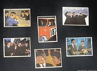 Six 1964 Topps Beatles Diary trading cards lying flat showing front color photos of the Beatles in various scenes, including a car and group shots.