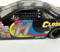 Side view showing detailed decal number 11 and sponsor logos on black stock car model with cage interior visible, approximately 8.25 inches in length.
