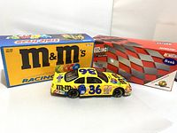 Photo showing stock car bank with original packaging including M&M's branded box and racing-themed display box.