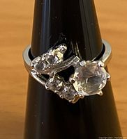 Front view of sparkly cocktail ring with clear stones on a ring display cone.