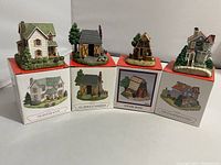 Four Liberty Falls miniature buildings on their boxes showing front and side views with detailed scenery and architecture.