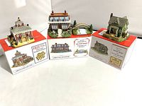 Three Liberty Falls miniature village buildings on closed original packaging boxes with promotional offers visible.
