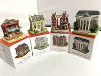 Four miniature Liberty Falls village buildings displayed on their original branded boxes, showing front views of each piece and their packaging