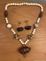 Full view of the pig jewelry set including the necklace and earrings laid out on a wooden surface.