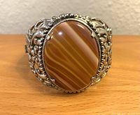 Front view of cuff bracelet showing detailed silver tone filigree and large oval red carnelian agate stone.