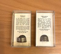 Two reproduction antique thimbles with background info in display cases, one Medieval and one Verulamium Roman style.