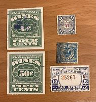 Top view showing front sides of 5 vintage tax revenue stamps on wood surface