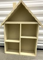 Front view of cream color wooden dollhouse stand with four compartments and pitched roof design.