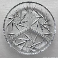 Top view of round divided serving plate showing detailed geometric starburst cut-glass design.