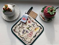 Image showing white fruit-themed ceramic server, red strawberry-shaped ceramic server, and floral-patterned potholder
