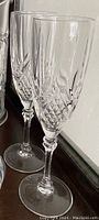 Photo showing two crystal champagne flute glasses with diamond cut design and clear stems and bases.