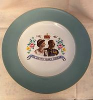 Top view of the commemorative Queen Elizabeth II Silver Jubilee plate showing the teal green border, gold trim, and central profile images of the Queen and Prince Philip with floral decoration and jubilee text.