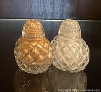 Pair of vintage crystal salt and pepper shakers, showing front and side views with diamond cut pattern and dome tops