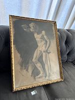 Full view of framed Bacchus drawing resting on a couch, showing the entire artwork and frame.