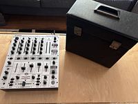 Behringer DJX700 mixer and vintage black record case on a wooden surface.