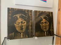 Pair of stylized portrait paintings of Indian women featuring gold jewelry and dark tones.
