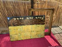 Photo showing the artwork resting against a wood frame and bamboo background.