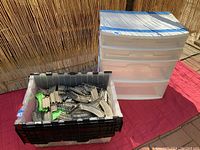 Photo showing the crate full of Thomas Trackmaster train tracks next to a 3-tier white plastic storage drawer unit.