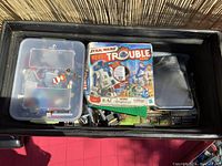 Inside view of open trunk showing boxed Star Wars Trouble game, LEGO pieces sorted in plastic containers, Minecraft materials, and assorted items inside trunk