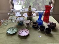 Full view of the lot showing Weck jars, ceramic tea pots and cups, vintage plates, and colored glass vases