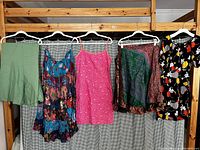 Six women's clothing items on hangers including shorts, dresses, and blouses in various colors and patterns