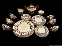 Full spread of all porcelain pieces laid out showing plates, cups, saucers, teapot, sugar bowl and creamer.