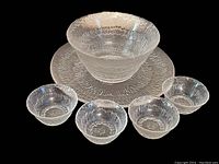 Full set of large serving platter, medium bowl, and four small bowls on black and patterned background.