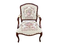 Front view of the vintage carved wood Louis XV style armchair with tapestry upholstery showing courting scene and floral designs.