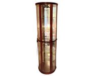 Full view of tall half-round wall display cabinet with dark wood framing, glass doors, glass shelves, and mirrored back panel, shown from front angle.