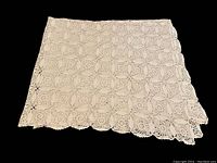 Full folded view of the crochet tablecloth showing pattern and edges.