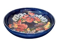 Photo showing the vintage Moorcroft ceramic bowl with hand-painted iris flowers and dark blue background, front angle.