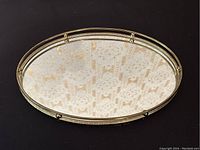 Full view of the vintage oval vanity display mirror showing the brass frame and reflective mirror surface.