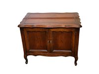 Front view of vintage walnut record cabinet with two paneled doors and scalloped edges on top surface