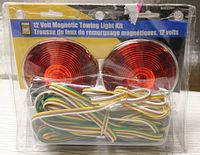 Front view of the 12 Volt Magnetic Towing Light Kit showing two round red-amber lights and wiring in clear plastic packaging.
