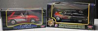 Two boxed die cast car models side by side: 1959 Corvette in red and white and a black flame-decorated vintage car.
