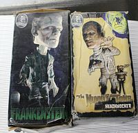 Two boxed headknocker bobbleheads, one Frankenstein and one mummy, in original packaging with character artwork on each box.