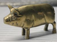 Side view of the brass pig figurine, showing detailed features and aged surface.