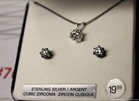 Photo of necklace and matching earrings displayed on a light cushioned background. Close up showing the clear cubic zirconia stones set in sterling silver.