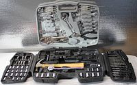Open carrying case displaying a wide variety of hand tools including sockets, drill bits, pliers, and snips arranged in molded compartments.
