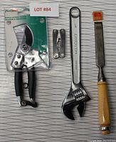Lot showing bypass pruning shears, small multi-tool, adjustable wrench, and wood chisel