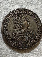 Close-up photo of obverse side of 1747 Spanish gold doubloon featuring monarch profile and legend text.