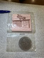 Reverse side of the coin packaging including the pink card with Rodmilla Credit Union building illustration.
