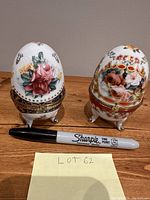 Two vintage Acko collector eggs standing side by side with Sharpie used for size comparison and a note labeled Lot 62.