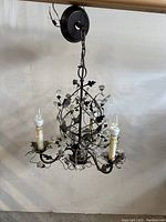 Full view of the metal chandelier showing chain, ceiling mount, and 3 light arms with candle style sockets and crystal decorations.